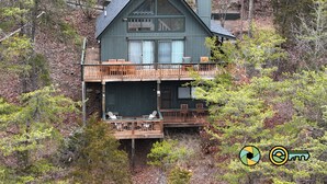 A two-story cabin with a balcony, surrounded by trees. - Par & Pine Lodge | Double decks w/ fire pit! (Basye)