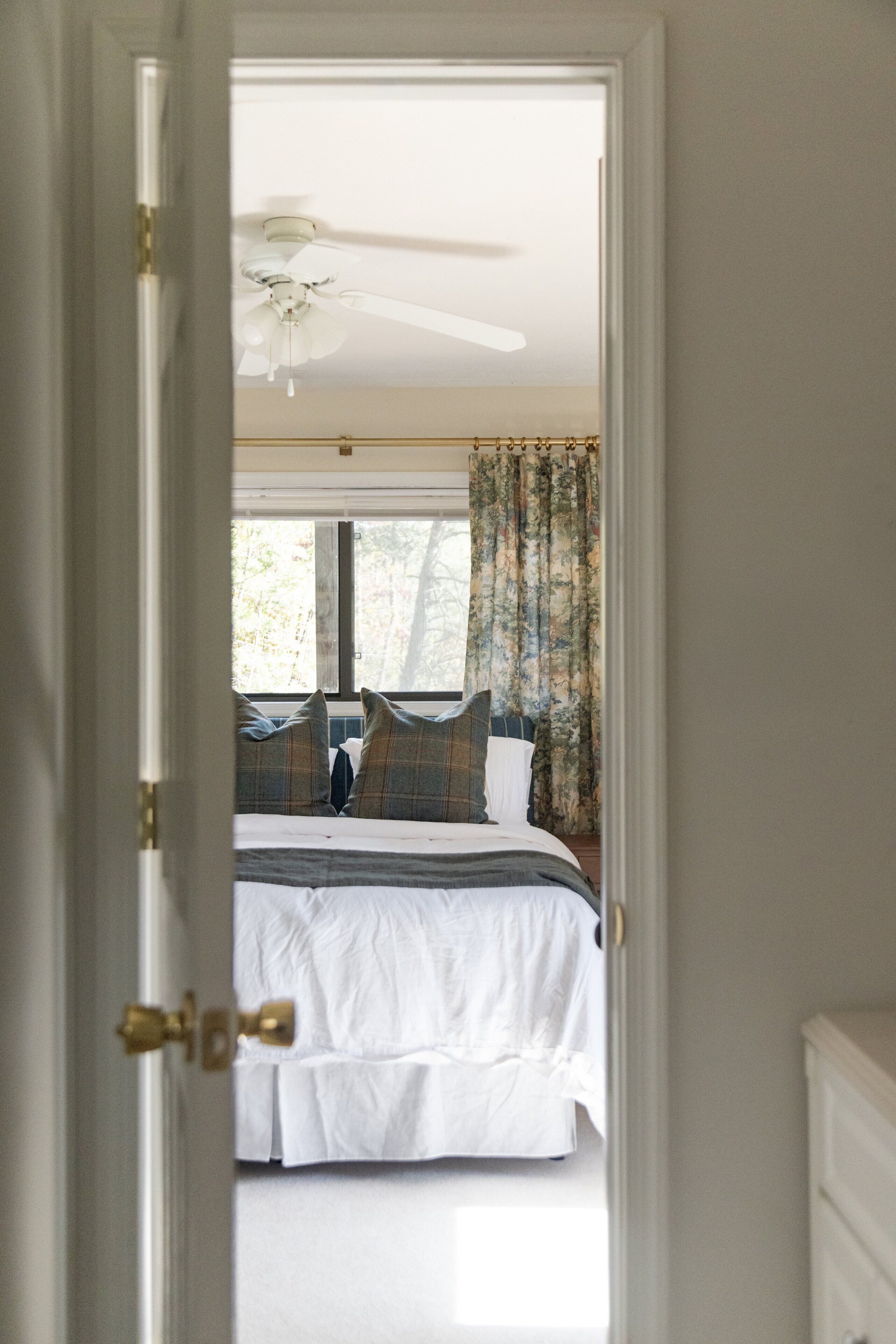A bedroom with a bed, curtains, and a ceiling fan.
