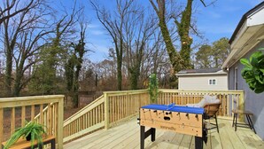 A wooden deck with a foosball table, a chair, and a small table with a plant. - 2 Bedroom Near Beltline, Mercedes Benz Stadium & State Farm Arena (Atlanta)