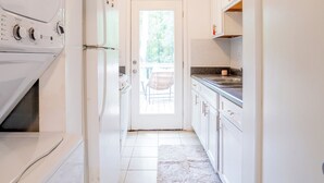 A narrow kitchen with white appliances, a tiled floor, and a view to an outdoor area. - 2 Bedroom Near Beltline, Mercedes Benz Stadium & State Farm Arena (Atlanta)