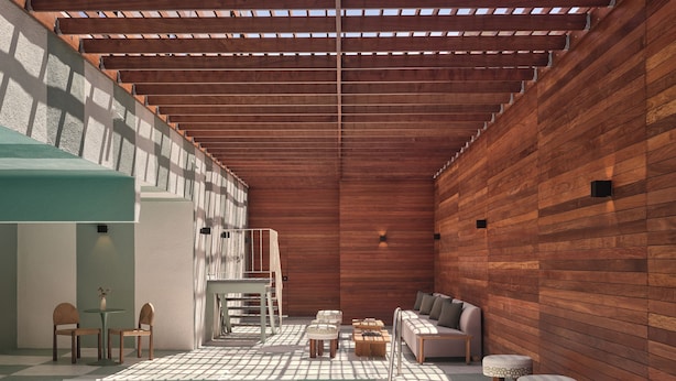 Un área de piscina con techo de madera, una zona de estar con sofá y sillones, y una pequeña mesa.