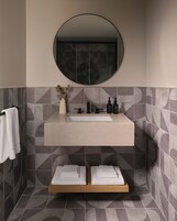 A bathroom with a round mirror, a sink, and two towel racks.