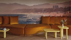 Una sala de estar con un sofá grande, dos mesitas y un mural de playa en la pared.