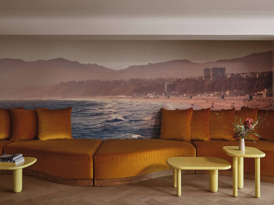 A living room with a large sofa, two small tables, and a beach mural on the wall.