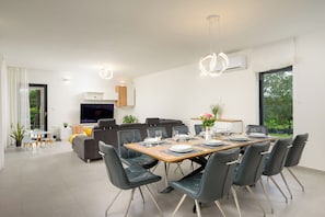 A modern dining area with a long table, black chairs, and a television in the background. - Villa Diego (Istria - Pula) (Prodol)