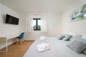 Ein Hotelzimmer mit einem Bett, einem Schreibtisch, einem Stuhl, einem Fernseher und einem Fenster mit Vorhängen.