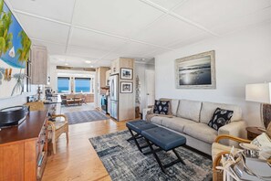 A spacious living area with a sofa, dining table, and kitchen. - Night Heron: Oceanfront Views + Walk to Dining (Kitty Hawk)