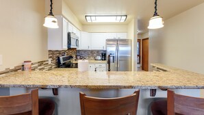 A kitchen with granite countertops, white cabinets, stainless steel appliances, and pendant lighting. - New! Patio, AC & Classic Comfort! (Bigfork)