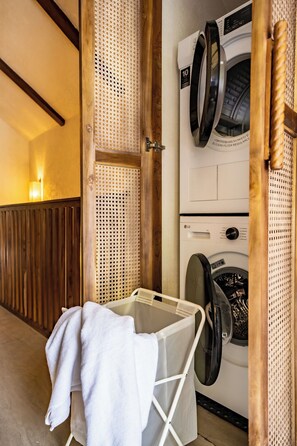 A laundry area with a washing machine, a drying rack, and a wooden wall with a perforated design. - Villa Mir Batu Uluwatu (Uluwatu)