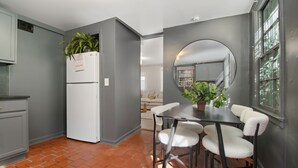 Une cuisine de taille réduite avec un réfrigérateur blanc, une table à manger avec quatre chaises et un grand miroir au mur.