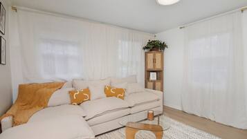 A modern living room with a beige sofa, a glass coffee table, and a wooden cabinet.