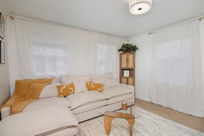 A modern living room with a beige sofa, a glass coffee table, and a wooden cabinet.
