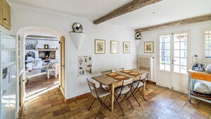 A dining area with a wooden table and chairs, a radiator, and framed pictures on the wall. - MAISON PROVENÇALE AVEC PISCINE (Saint-Paul-De-Vence)