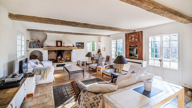 A spacious living room with a fireplace, wooden beams, and large windows. - MAISON PROVENÇALE AVEC PISCINE (Saint-Paul-De-Vence)