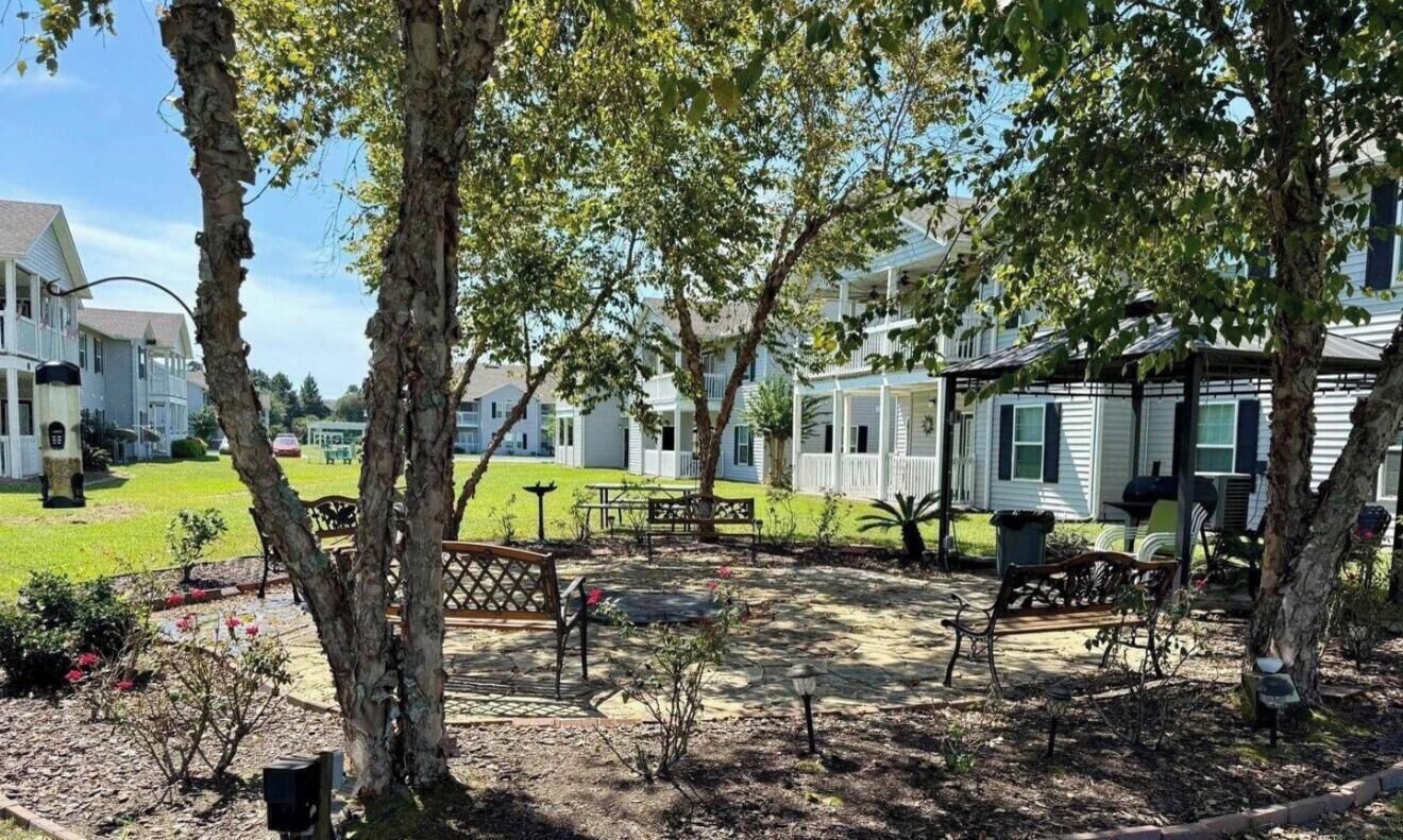 A residential area with multiple houses, a grassy lawn, and outdoor seating.