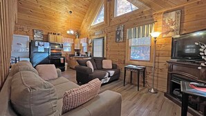 A cozy cabin interior with a living room, kitchen, and a TV. - Moonlight Ridge Cabin (Bryson City)