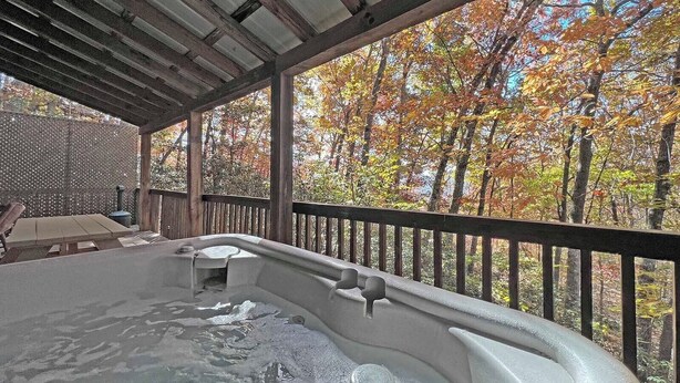 A hot tub under a wooden pergola with a view of autumn trees. - Moonlight Ridge Cabin (Bryson City)