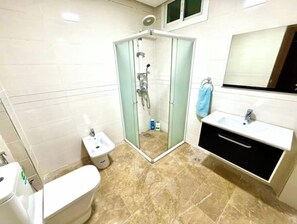 Une salle de bain avec une douche à parois de verre, des toilettes, un lavabo et un miroir.