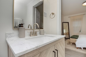 A bathroom with a marble countertop, a sink, a mirror, and a door leading to a bedroom. - Fabulous 1-bedroom apartment in vibrant Atlanta Near Midtown, Emory University (Atlanta)