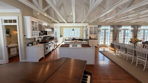 Une cuisine spacieuse avec un îlot central, un plancher en bois et un piano.