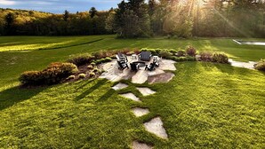 Une pelouse bien entretenue, agrémentée d’une terrasse en pierre et de mobilier d’extérieur.