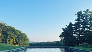 Un canal rempli d’eau, bordé d’arbres et surplombé d’un ciel dégagé.