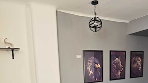 Ein Schlafzimmer mit einem Bett, einem Sessel und drei gerahmten Bildern an der Wand.