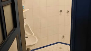 Ein kleines Badezimmer mit Fliesen, einer Dusche, einer Toilette und einem Waschbecken.