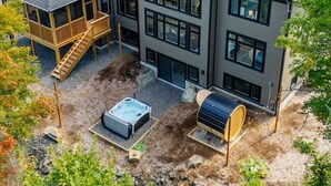 Una casa moderna de dos pisos con un balcón, un jacuzzi y una sauna en el patio trasero.