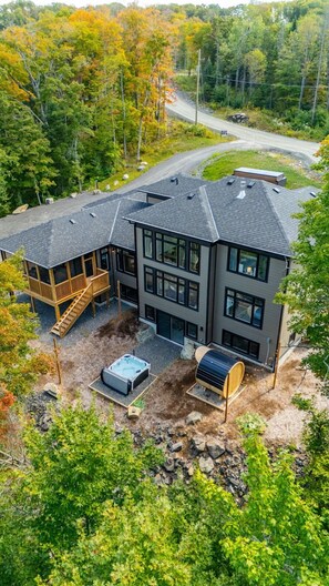 Ein modernes, zweistöckiges Haus mit einer Terrasse, einem Whirlpool und einer Sauna im Garten.