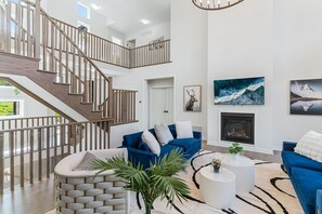 Un salon spacieux avec un canapé bleu, une cheminée et un escalier menant à l’étage supérieur.