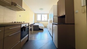 A compact kitchen with modern appliances, a dining area, and a window providing natural light. - Kamienna Urban Comfort Studio (Wrocław)