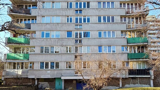 A multi-story residential building with balconies, a green awning on the ground floor, and a clear sky in the background. - Kamienna Urban Comfort Studio (Wrocław)