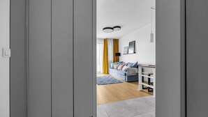 Una sala de estar moderna con un armario gris, un sofá azul y piso de madera.