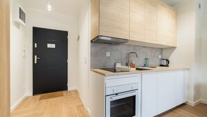 Una cocina moderna con armarios blancos, una puerta negra y encimera de madera.