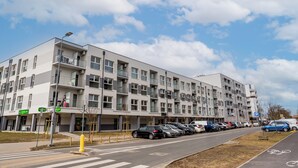 Un edificio residencial de varios pisos, con balcones, un estacionamiento y cielo despejado.