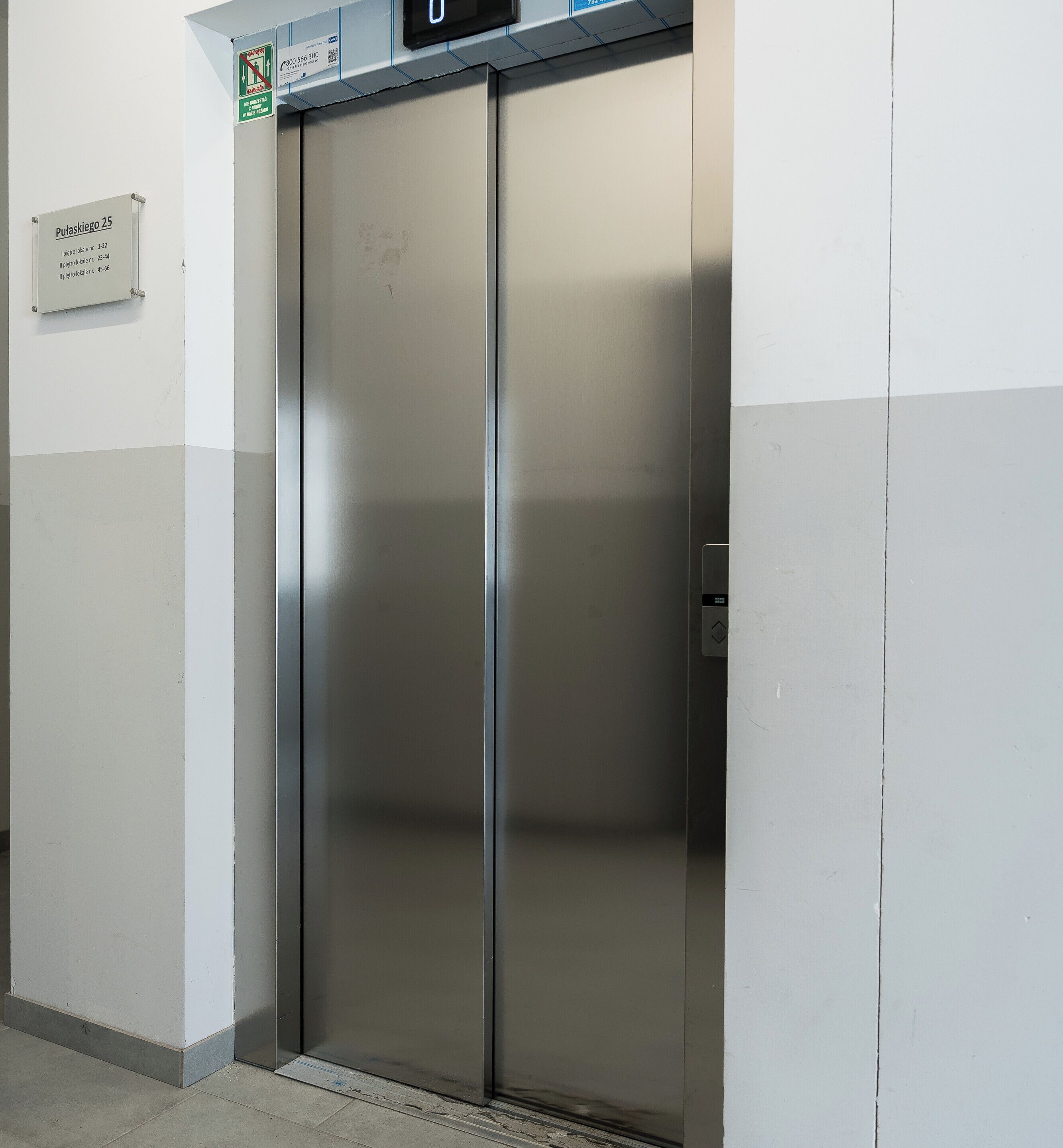 Un ascensor metálico con una pantalla digital que muestra '0'.