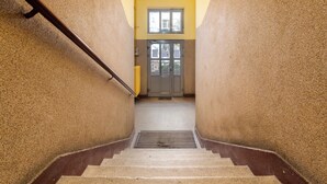 Una escalera con barandilla que conduce a una puerta con un ventanal encima.