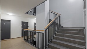 Un escalier avec une rampe en métal et une main courante en bois, menant à l’étage supérieur.