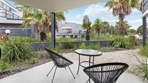 An outdoor patio area with two black wireframe chairs and a small round table. - 2 Bedroom Open plan,combined living & dining areas with fully self contained kitchen & laundry. (Batehaven)