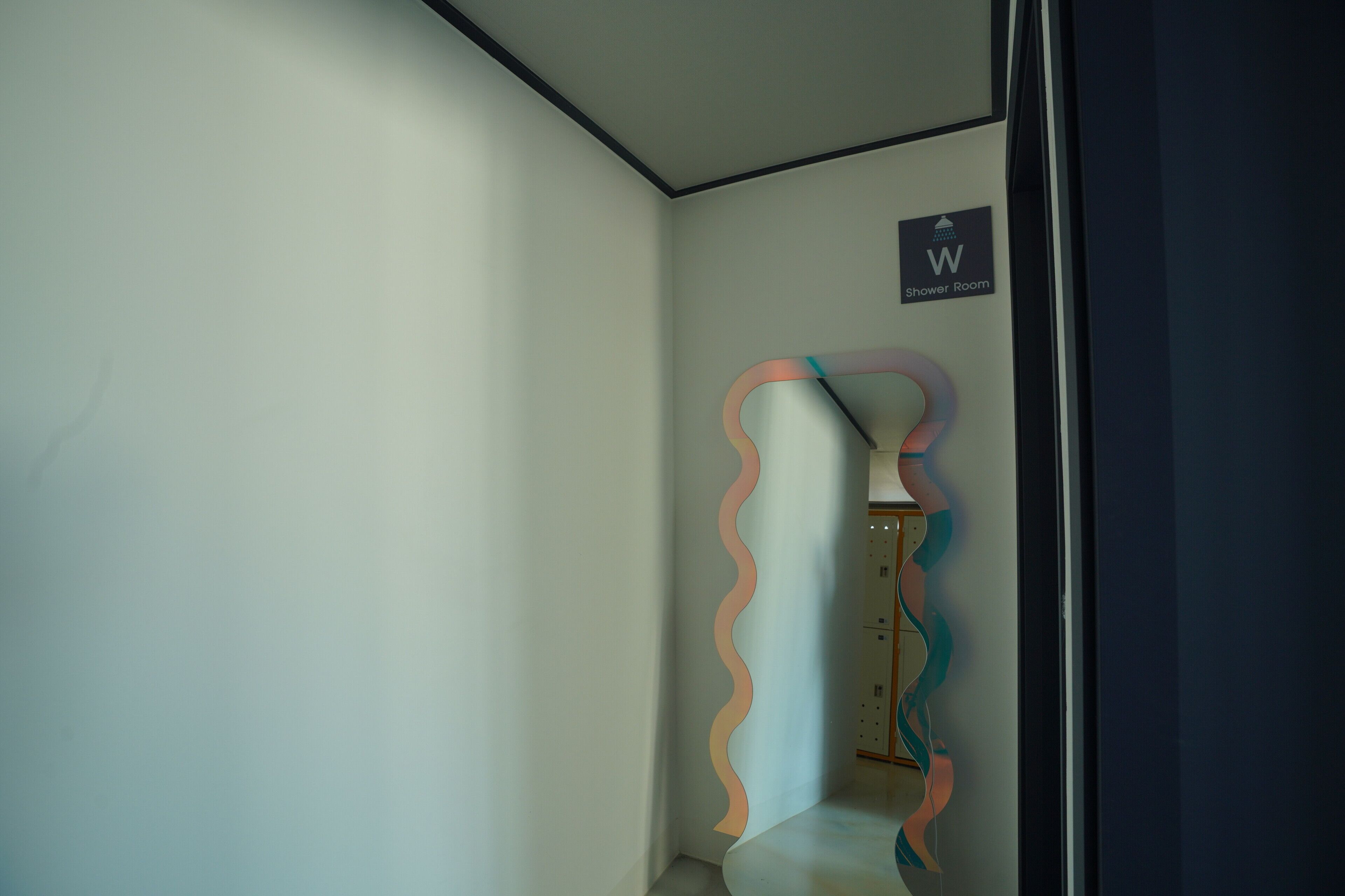 A corner of a room with a wavy wall design, a shower room sign, and a door frame.