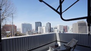 Un balcon donnant sur le panorama urbain, une table et deux chaises.