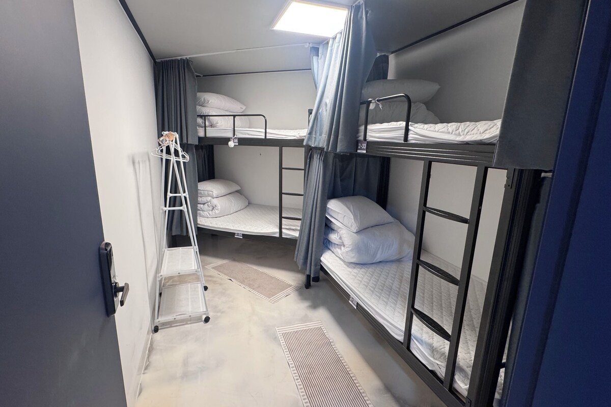 A compact room with bunk beds, a ladder, and a small table.