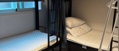 A bunk bed room with a window, curtains, and a ladder.