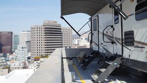 Une terrasse sur le toit offrant une vue sur le paysage urbain, un espace extérieur couvert et un escalier menant à une plateforme.