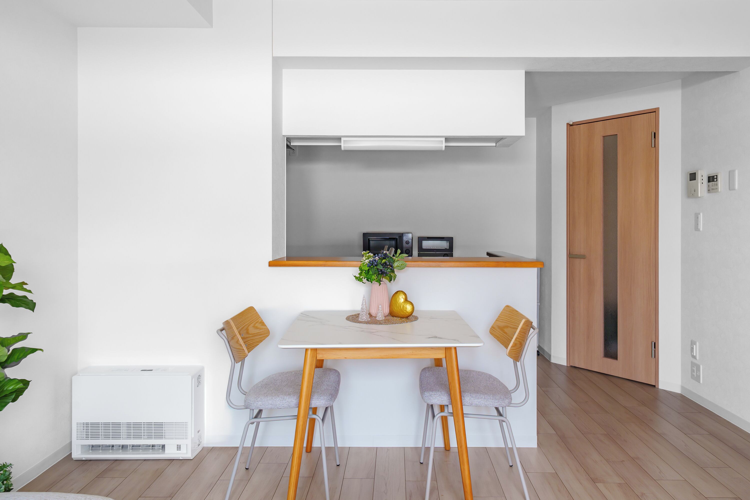 A compact kitchen with a white countertop, a microwave, and a wooden door.