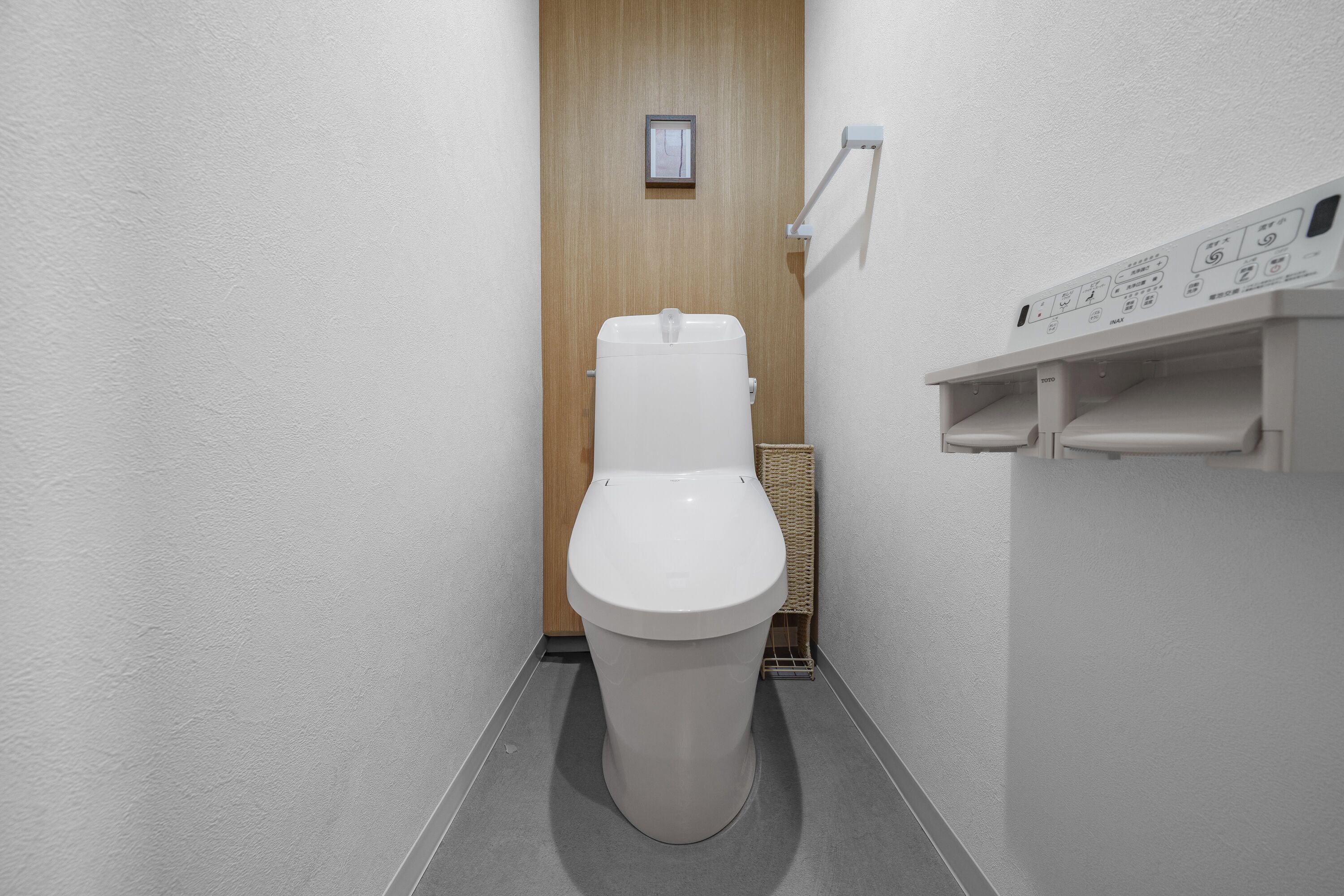 Un baño moderno con un inodoro blanco, una puerta de madera y un panel de control en la pared.