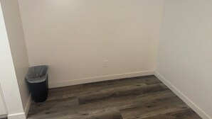 Habitación de esquina con paredes blancas y suelo de madera oscura.