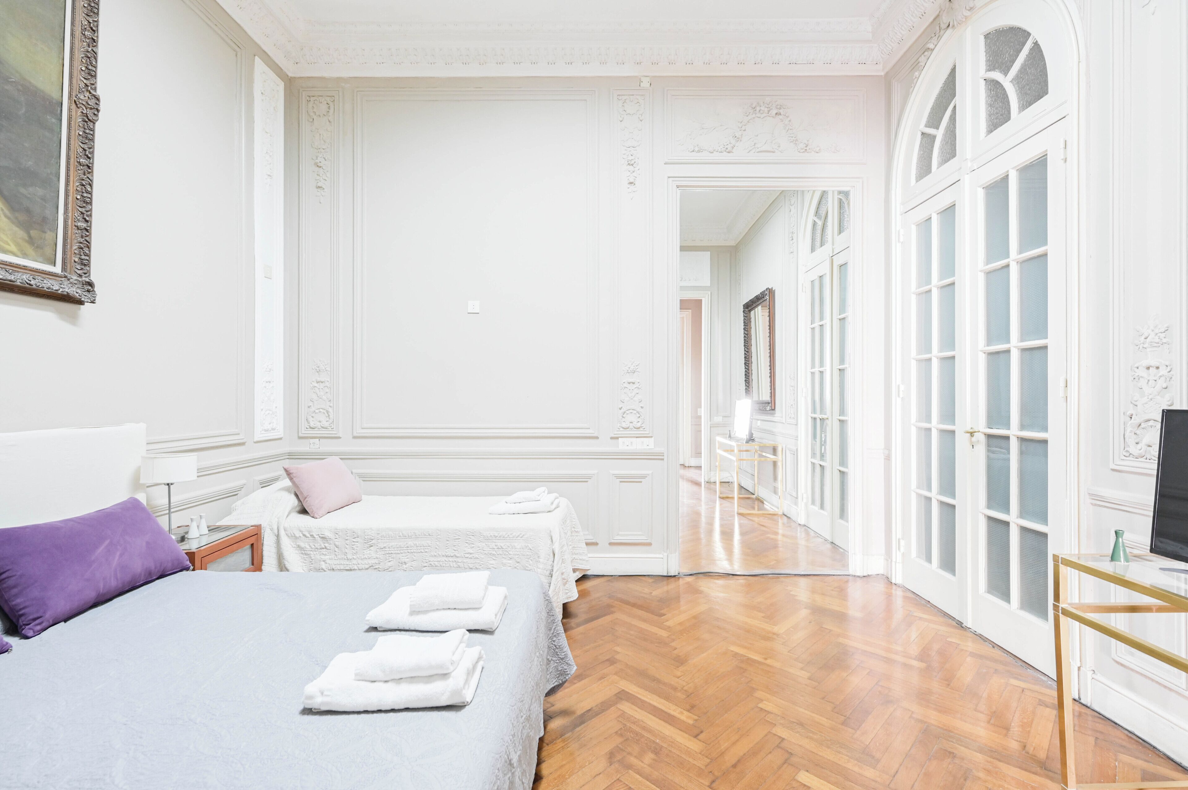 Une chambre d’hôtel avec deux lits, une télévision et un couloir avec des portes.