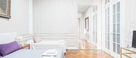 Une chambre d’hôtel avec deux lits, une télévision et un couloir avec des portes.